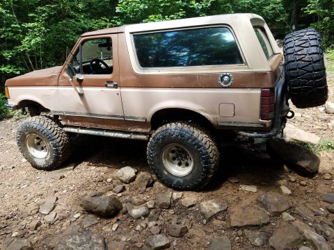 1988 Ford Bronco - This lifted Ford Bronco navigates a rocky, wooded trail.
