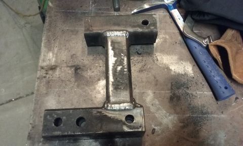 1995 Ford Bronco - A custom-welded metal component rests on a workshop surface, alongside tools.