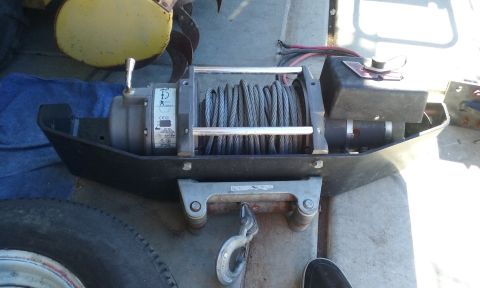 1995 Ford Bronco - A winch with a steel cable and hook is shown, mounted on a black base.