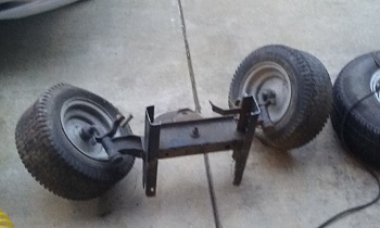1995 Ford Bronco - A disassembled axle assembly with wheels and tires sits on a concrete surface.