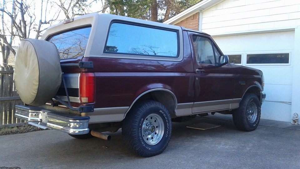 1996 Ford Bronco parked in driveway next to garage, rear-mounted spare tire visible
