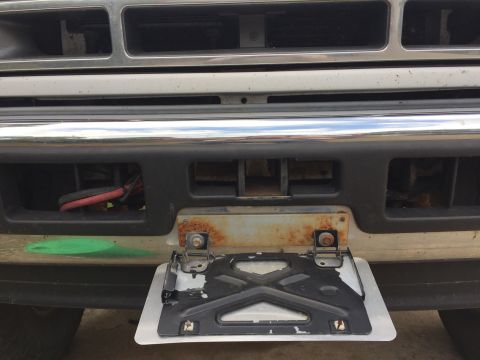 1996 Ford Bronco - The front bumper shows a license plate bracket with rust and some wiring peeking out from behind.