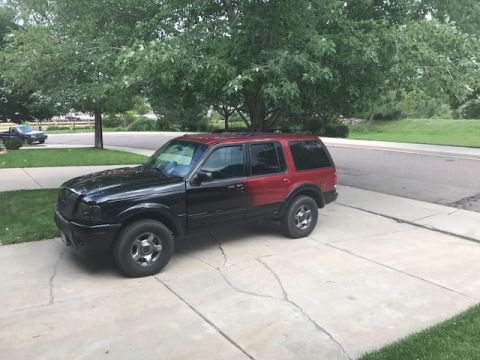 2000 Ford Explorer - A two-tone 2000 Ford Explorer is parked on a concrete driveway under trees.