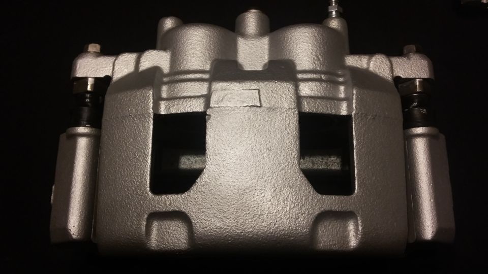 Silver painted brake caliper with visible bolts and brake pads