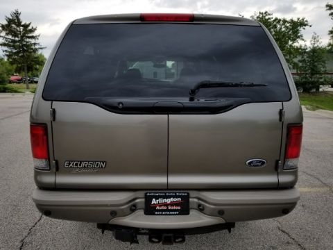2003 Ford Excursion - Rear view of a tan 2003 Ford Excursion SUV, with visible badging and a license plate frame from a dealership.
