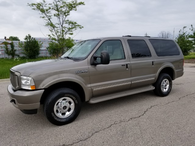 Tan Ford Excursion SUV parked on asphalt, side view