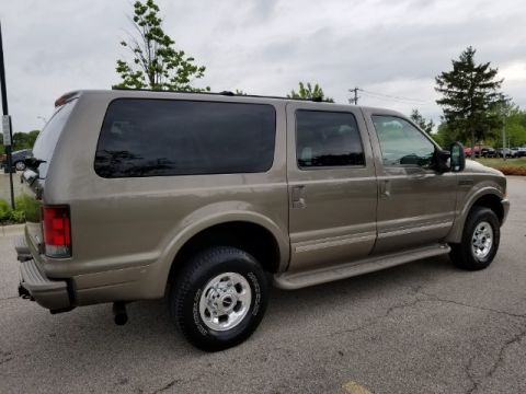 2003 Ford Excursion - Rear 3/4 view of a tan 2003 Ford Excursion SUV parked on asphalt.