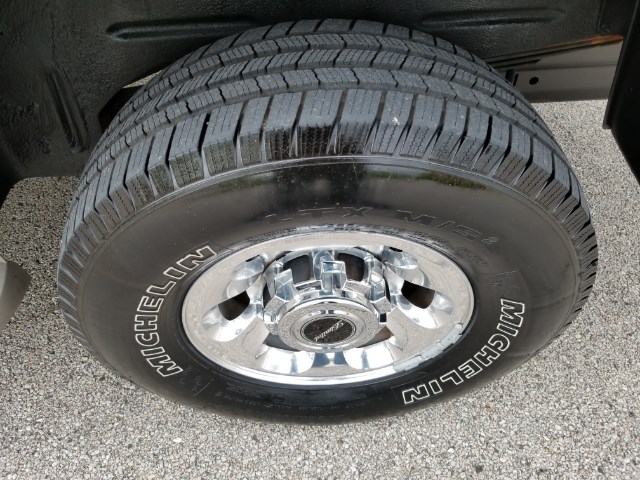 Close-up of a Michelin tire on a chrome wheel. The wheel has a center cap with a logo