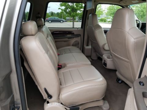 2003 Ford Excursion - The interior of a large SUV features multiple rows of tan leather seats and a rear entertainment screen.