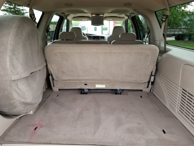 Rear seats folded down in an SUV, showing cargo area. Spare tire cover on left