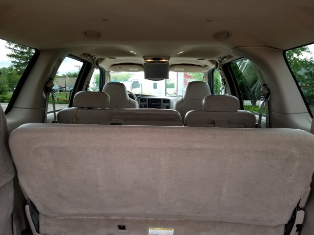 Tan interior of a large SUV, showing folded rear seats, overhead console with screen, and front seats