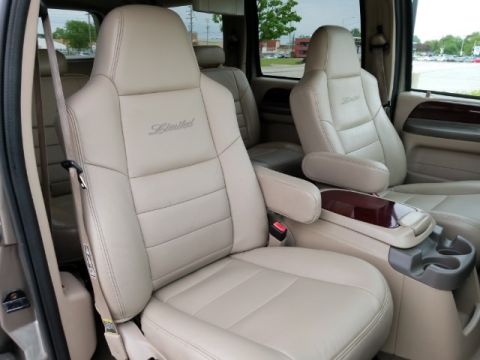 2003 Ford Excursion - The interior features tan leather seats with 'Limited' badging and a wood-accented center console with cup holders.