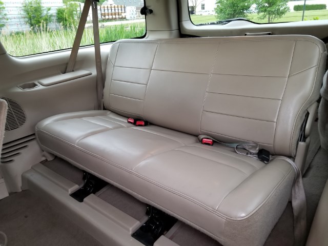 Beige leather rear bench seat with red seatbelt buckles in a 2003 Ford Excursion