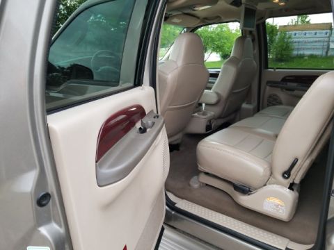2003 Ford Excursion - The interior of a large SUV is shown, tan leather seats and a wood-accented door panel.