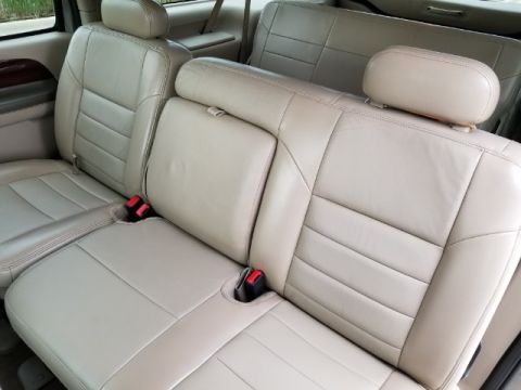 2003 Ford Excursion - The interior of a 2003 Ford Excursion shows tan leather seats with visible seat belts and headrests.
