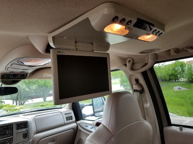 Overhead flip-down rear entertainment screen in a vehicle interior with tan trim