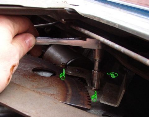 1994 Ford Bronco - Hand lifting trim to reveal a window regulator's toothed sector gear and motor shaft, marked with pointer arrows.