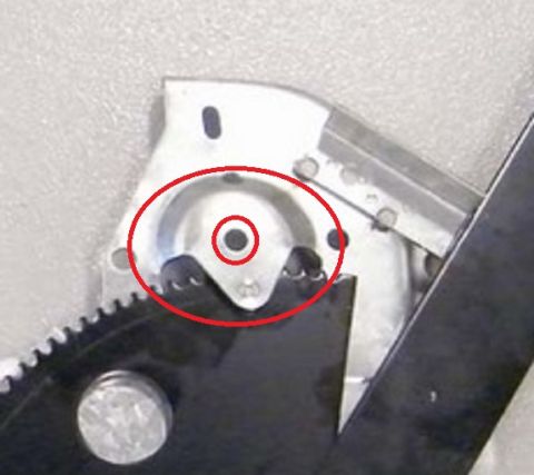 1994 Ford Bronco - Detail photo of a window regulator's riveted pivot plate and sector gear, highlighted with a red oval.