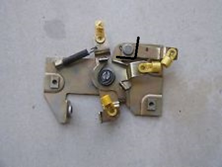 1994 Ford Bronco - Bench photo of a metal tailgate window switch and latch contact assembly with brass terminals.