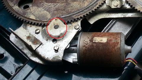 1994 Ford Bronco - Photo of a window regulator sector gear and electric motor, with a pivot point circled in red.