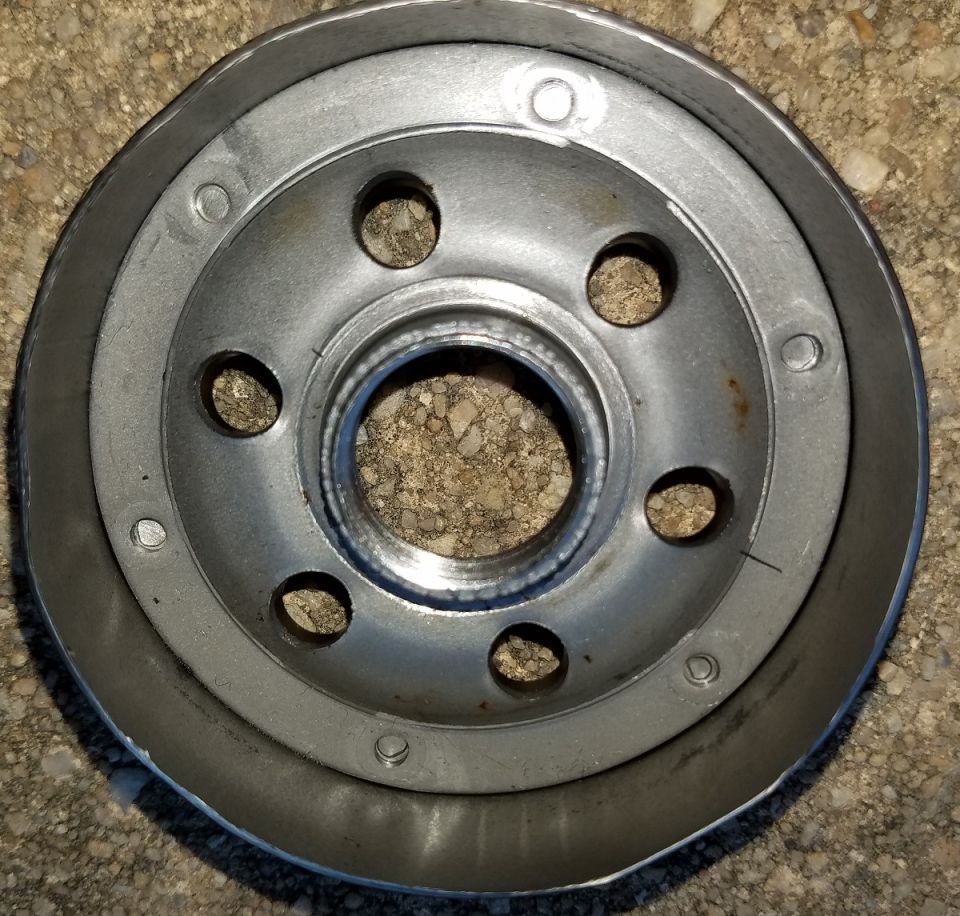 Silver oil filter with holes on concrete