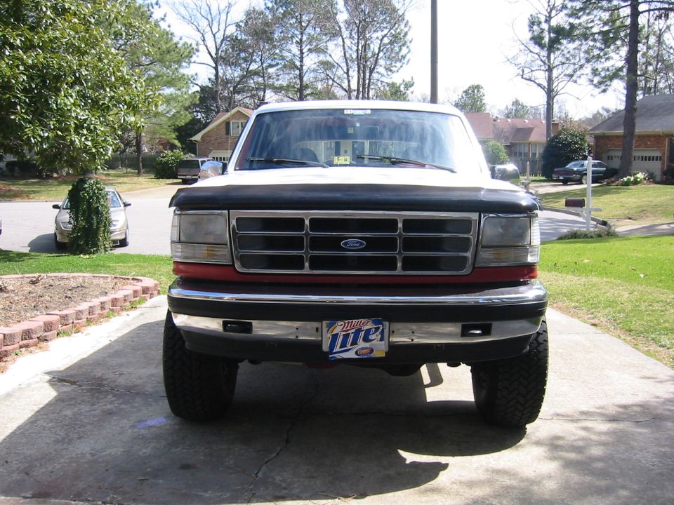Front view of lifted white and red Ford Bronco with black hood deflector and Miller Lite front plate in driveway
