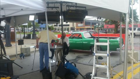 1971 Ford Ranchero - A green 1971 Ford Ranchero is parked under a tent with filming equipment. Two men are seated at a table next to the vehicle, with a ladder…