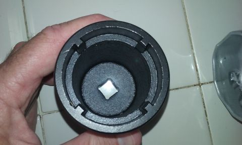 1995 Ford Bronco - A hand holds a black metal socket with a square opening at the bottom, resting on a tiled surface.