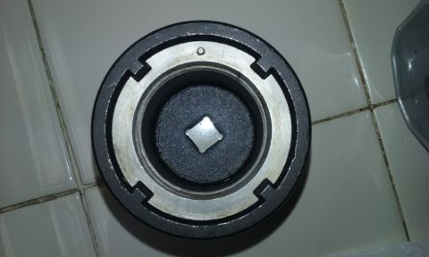 1995 Ford Bronco - A close-up, top-down view of a socket wrench adapter with a square drive opening. The adapter is black and silver and rests on a tiled surf…