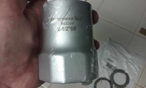 1995 Ford Bronco - A hand holds a silver socket wrench tool with "Performance Tool N83244 2-1/2"6R" engraved on it. The tool is partially wrapped in clear pla…