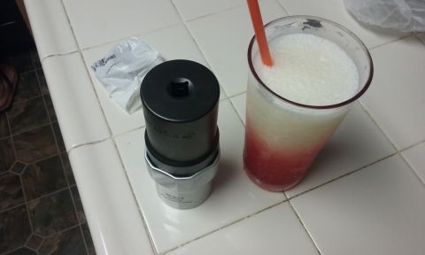 1995 Ford Bronco - A black oil filter wrench sits next to a layered red and white frozen drink in a clear glass with a straw. A small white packet is also vis…