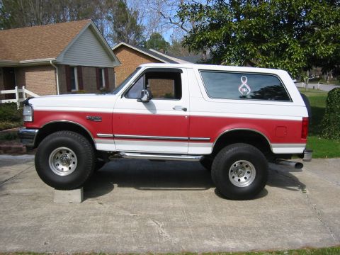 1993 Ford Bronco - This two-tone Ford Bronco, likely from the early 1990s, is shown from the side with oversized wheels.