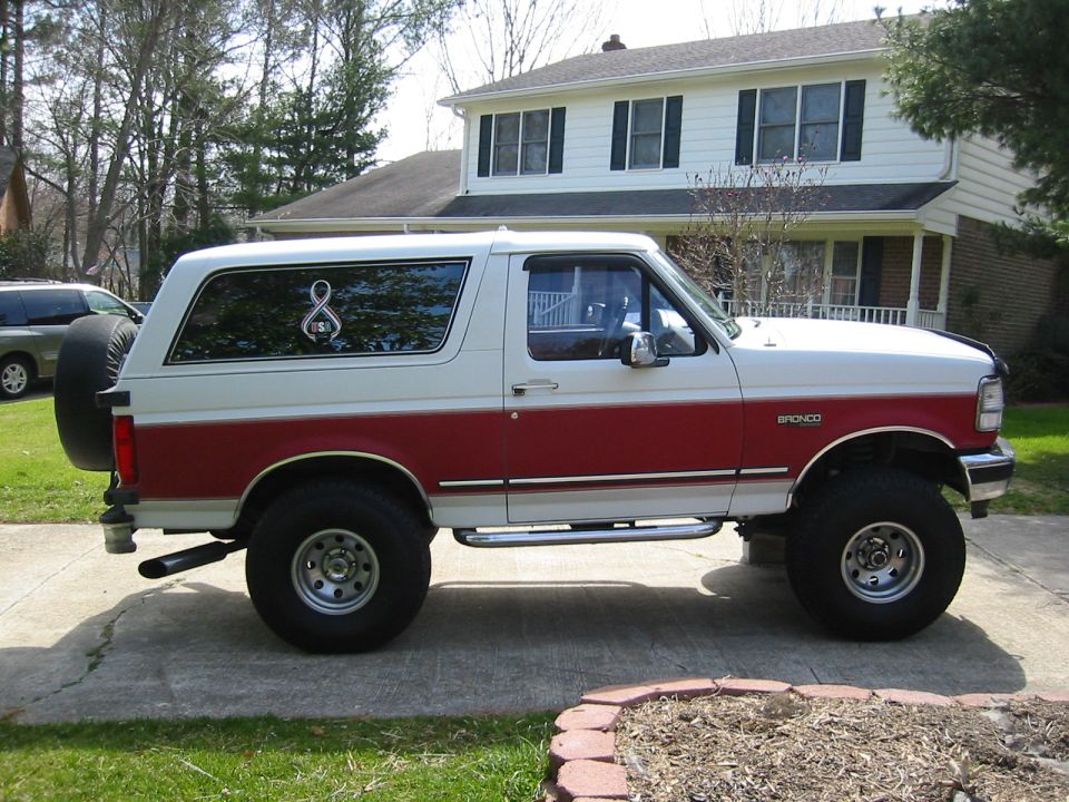 1993 Ford Bronco, two-tone white and red paint, side view. Spare tire mounted on rear door