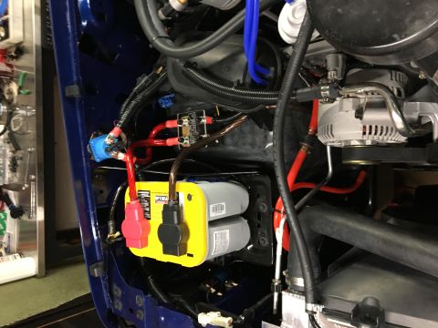 1996 Ford Bronco - A close-up view of the engine bay of a vehicle, showing a blue painted fender, an Optima yellow top battery, and various electrical compone…