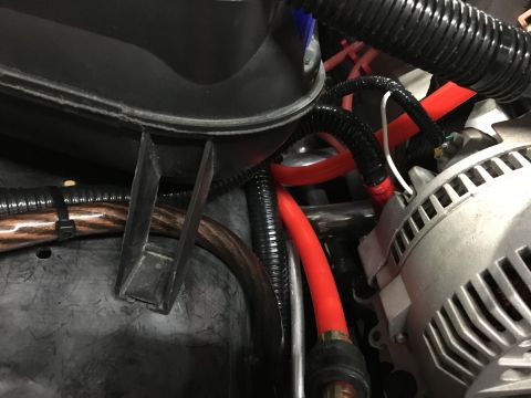 1996 Ford Bronco - A close-up view of automotive wiring and an alternator, likely from a 1996 Ford Bronco, showing red cables, black protective conduit, and a…