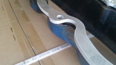 1981 Ford Bronco - A close-up view shows a silver metal suspension part with a hole in it, resting on a blue metal component. A white measuring tape with Span…