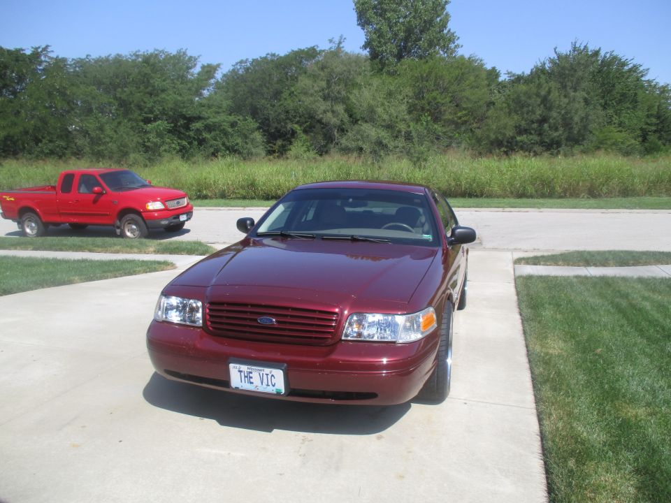 Maroon Ford Crown Victoria parked on driveway in front of red Ford F-150.