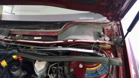 2002 Pontiac Grand Prix - The engine bay of a red Pontiac Grand Prix is shown with the hood open, revealing various components and wiring near the windshield cowl.