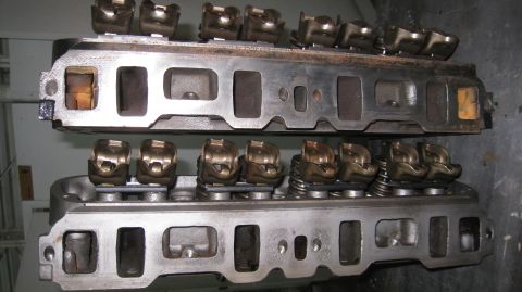 1996 Ford Bronco - Two Ford engine cylinder heads are stacked on top of each other. The bottom cylinder head has rocker arms and valve springs visible.