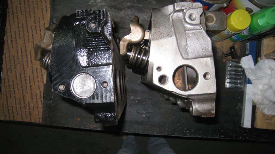 Two engine cylinder heads, one black, one aluminum, with valve train components visible.