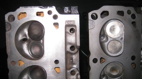 1996 Ford Bronco - Close-up view of two cast iron cylinder heads, likely from a Ford engine, showing intake and exhaust ports, valve seats, and combustion cha…