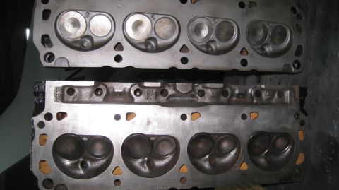 1996 Ford Bronco - Two cast iron cylinder heads are shown, stacked one above the other. The top head displays four combustion chambers, each with two circular…