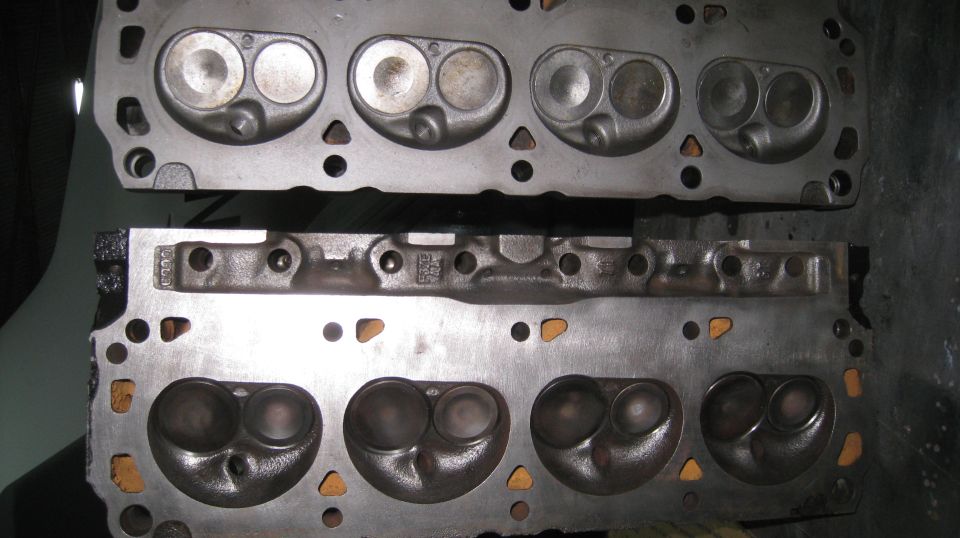 Two cast iron cylinder heads with visible valve openings and combustion chambers.