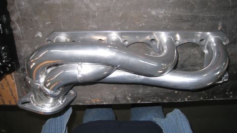 1996 Ford Bronco - A polished aluminum exhaust manifold is shown mounted on a workbench. The manifold has four primary pipes that merge into a single collecto…