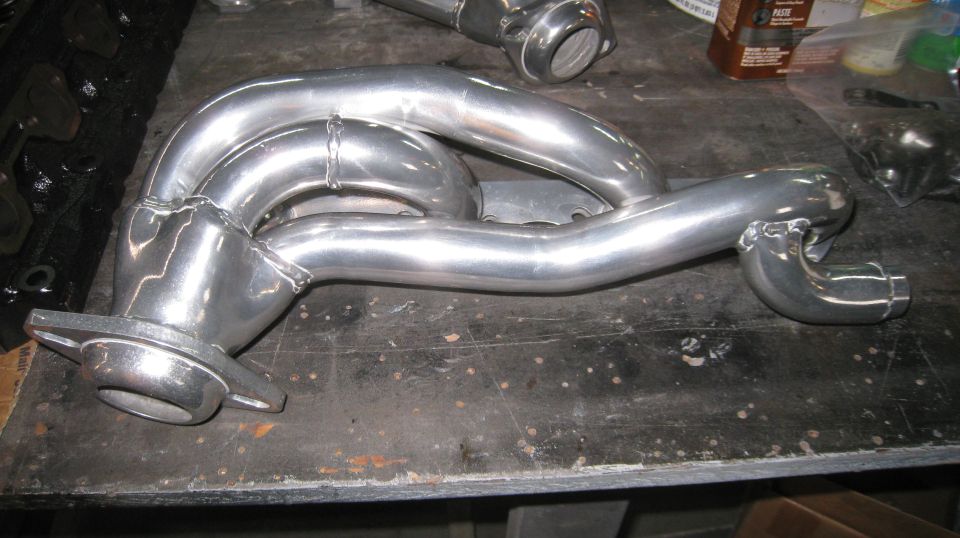 Polished aluminum exhaust manifold with multiple pipes and welds