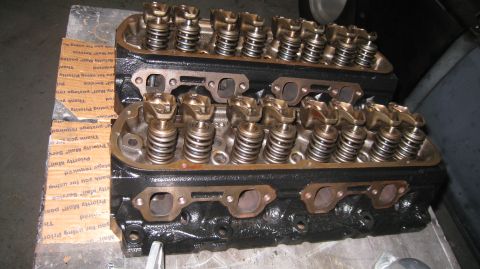 1996 Ford Bronco - Two black V8 engine cylinder heads with visible rocker arms and valve springs are placed on top of cardboard packaging. The cylinder heads…