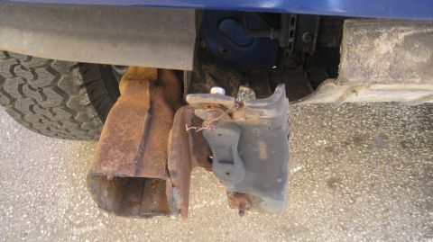 1996 Ford Bronco - The rusted front bumper bracket and a portion of the tire are visible on a blue vehicle. The vehicle appears to be an SUV or truck.