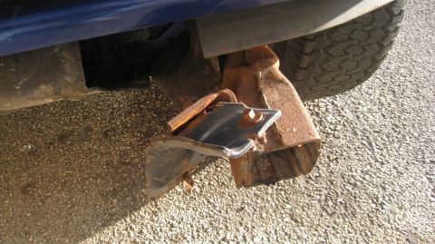 1996 Ford Bronco - The rear driver's side of a dark blue vehicle shows significant damage to the bumper and frame, with rusted metal components exposed. A por…