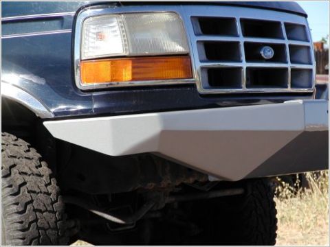1996 Ford Bronco - Close-up of the front corner of a dark blue Ford Bronco with a custom gray aftermarket bumper. The vehicle features a chrome grille and cle…