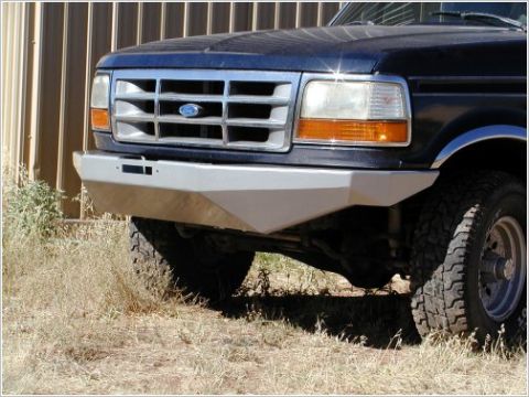 1996 Ford Bronco - The front bumper and grille of a dark blue 1990s Ford Bronco are visible, with a silver aftermarket bumper installed. The vehicle is parked…